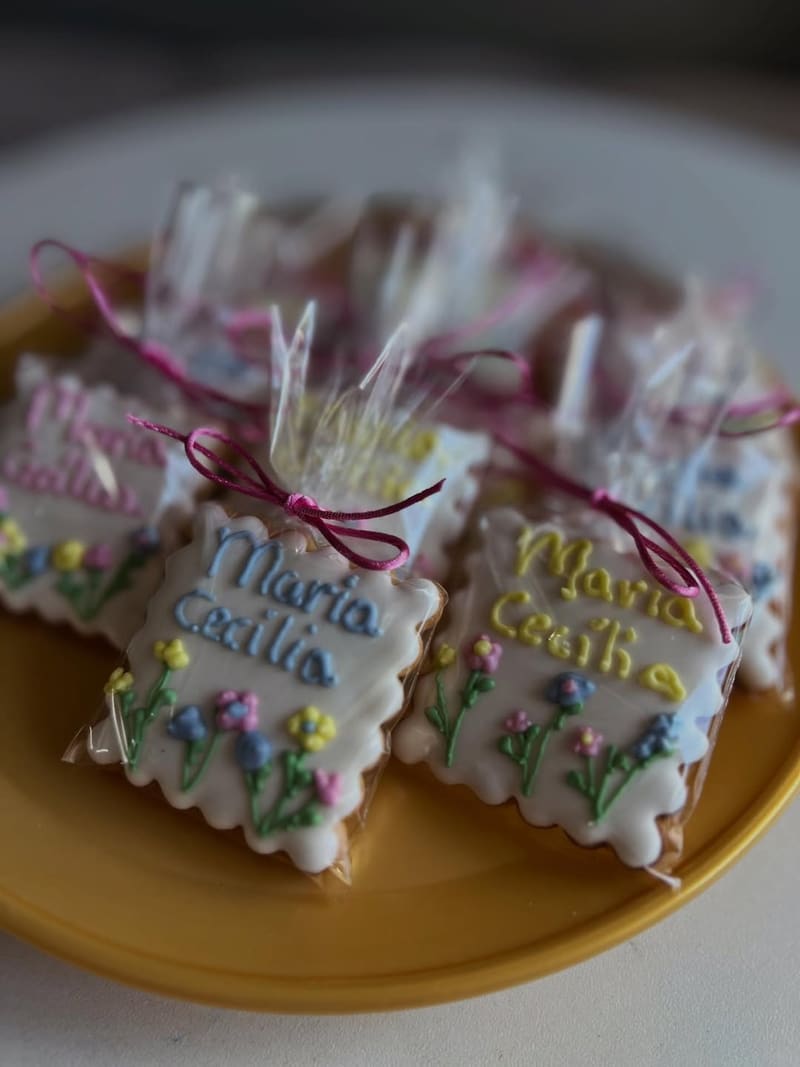 Lembrancinhas de biscoito decorado em tons de rosa, embaladas com laço e tag com o nome Maria Cecília