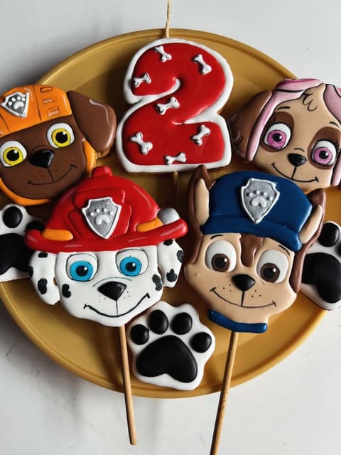 Biscoitos decorados de personagens de desenho animado e o número 2, sobre um prato dourado