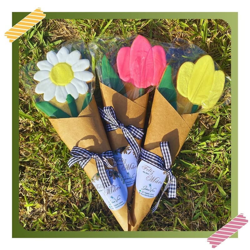 Biscoitos em formato de flores — margarida e tulipas — embrulhados em cones de papel kraft com laço