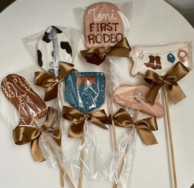 Biscoitos em paleta marrom e creme com tema country: chapéu, ferradura e placa escrita First Rodeo