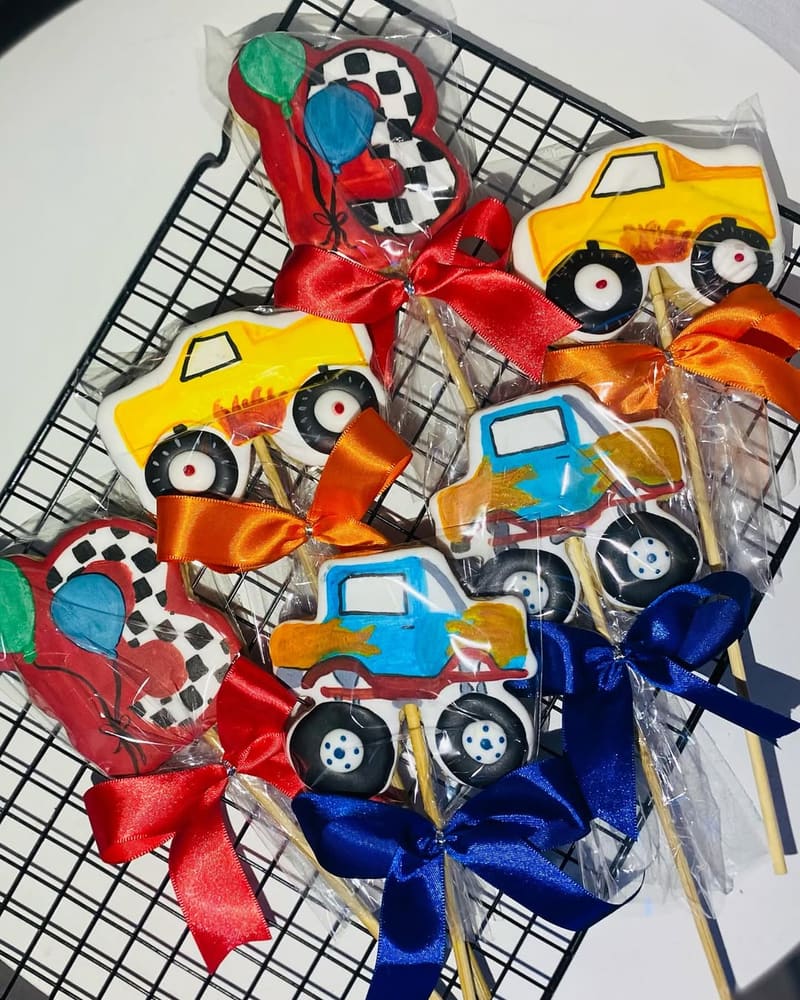 Biscoitos decorados de caminhão, trator e escavadeira, embalados com laço azul e vermelho